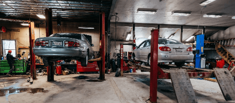 Auto Repair | Rowes Garage Inc. in Corinth, ME.Image of an interior of an auto garage shop with mechanics and 2 cars for auto repair.