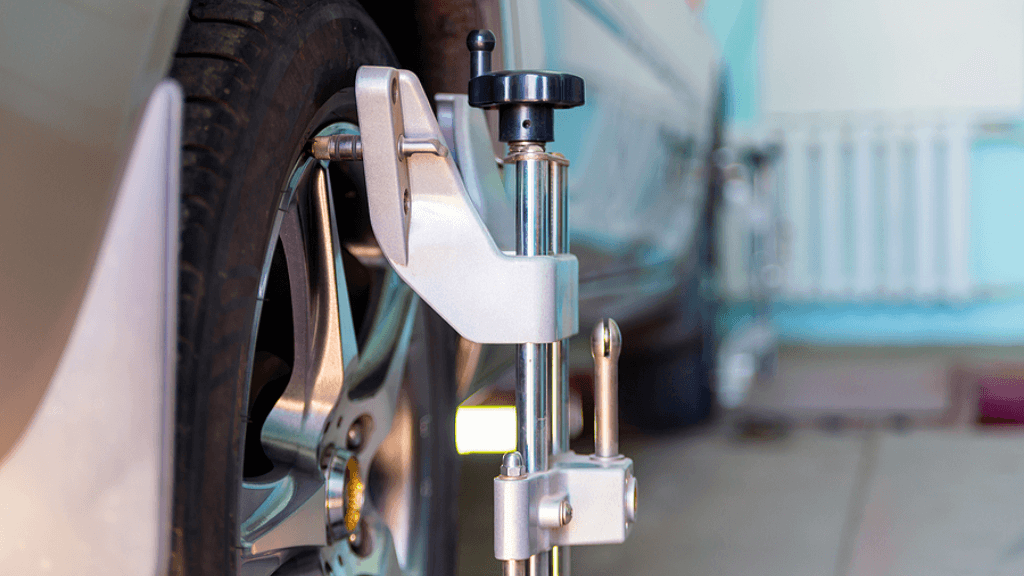 Alignments | Rowes Garage Inc. in Corinth, ME. Closeup image of a car undergoing wheel alignment in an auto shop garage, with an alignment sensor attached to a tire.
